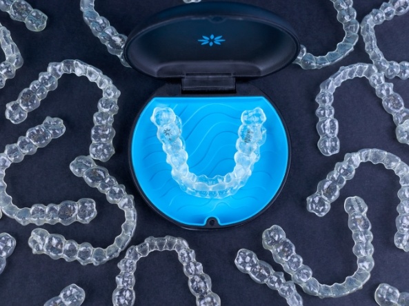 Several clear aligners with one in its carrying case