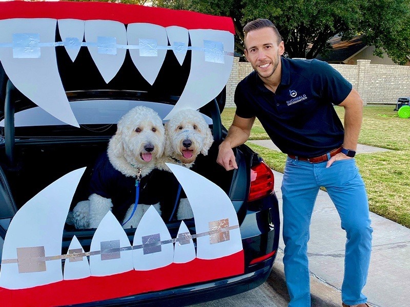 Doctor Buchwald with two dogs in car trunk decorated with vampire fangs with braces