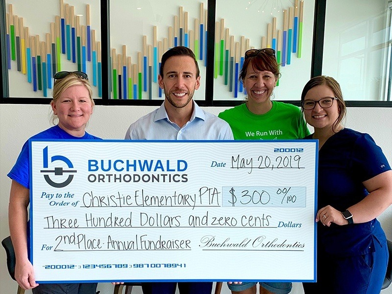 Doctor Buchwald with teachers holding giant check from Buchwald Orthodontics to Christie Elementary P T A