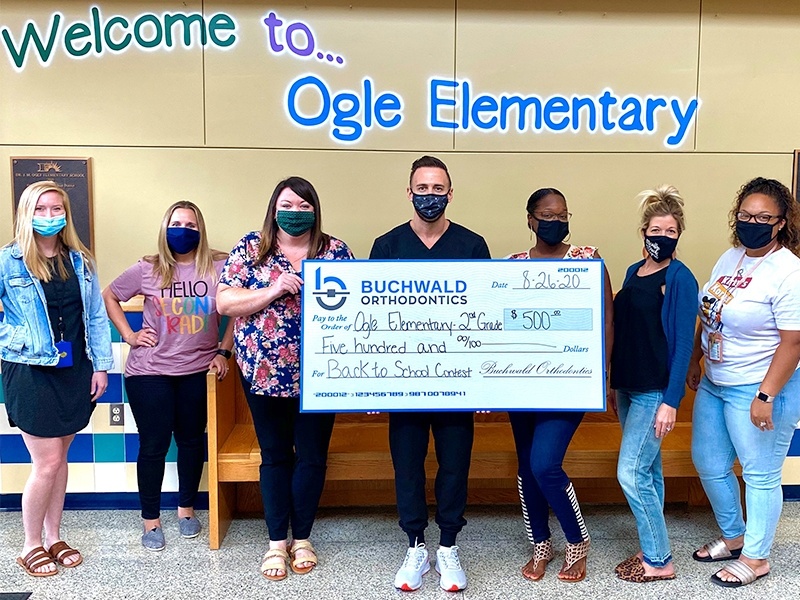 Doctor Buchwald holding giant check from Buchwald Orthodontics to Ogle Elementary School