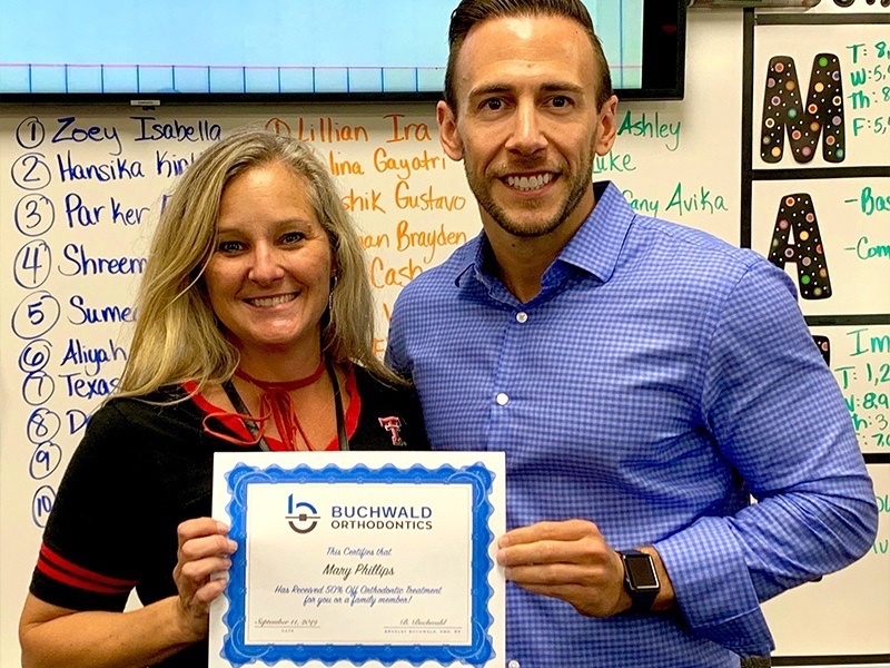 Doctor Buchwald with a woman holding a certificate for 50 percent off orthodontic treatment