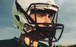 Man in football helmet with athletic mouthguard attached