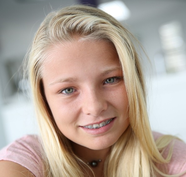 Young blonde girl smiling with metal braces in Prosper
